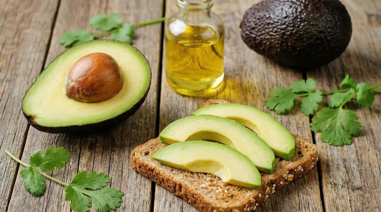 Avocado tagliato e fette su pane ai cereali con una bottiglietta di olio su tavolo di legno