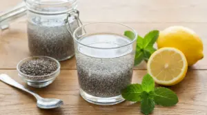 Bicchiere di acqua di chia con semi idratati, limone e foglie di menta su tavolo di legno