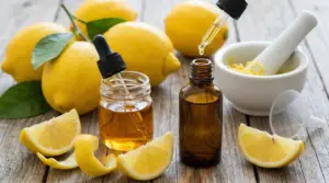 Bottiglie con contagocce e olio essenziale di limone, limoni interi e spicchi su tavolo di legno